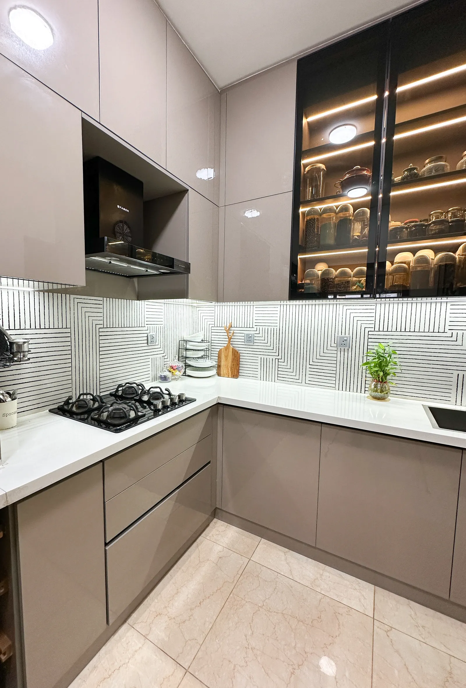 Kitchen corner with lit glass-front crockery cabinet — Somani's Residence